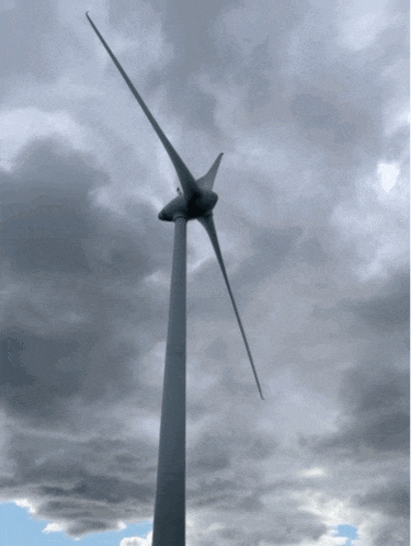 a wind turbine against a cloudy sky with a blue sky in the background