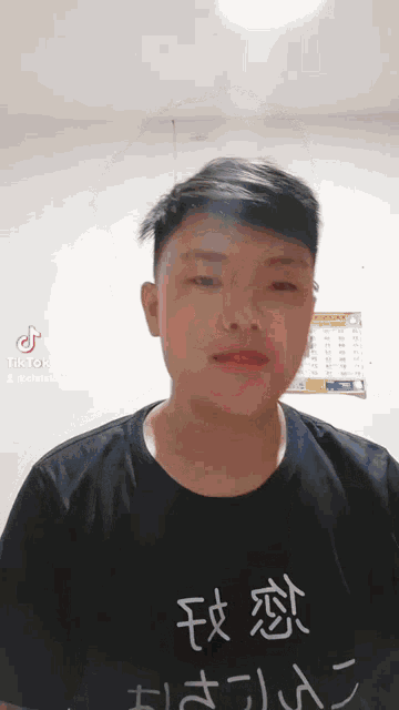 a young man is wearing a black shirt with chinese characters on it