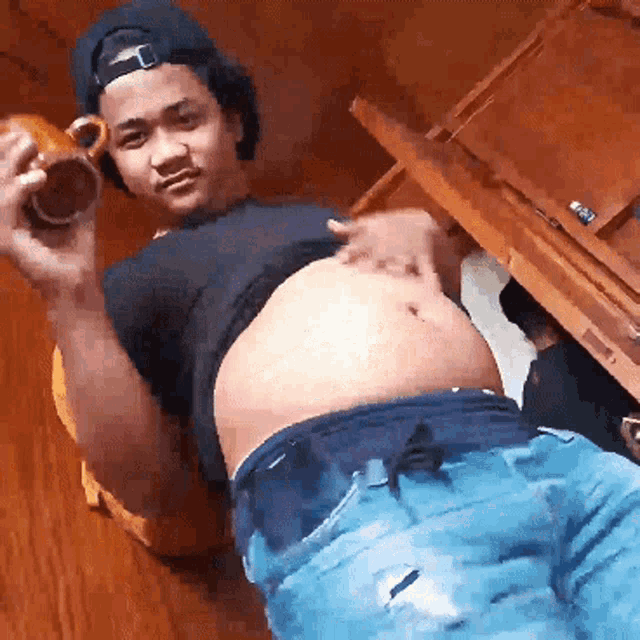 a man with a very large belly is holding a mug