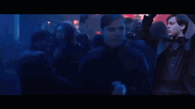 a man in a black suit is dancing in a crowd of people .