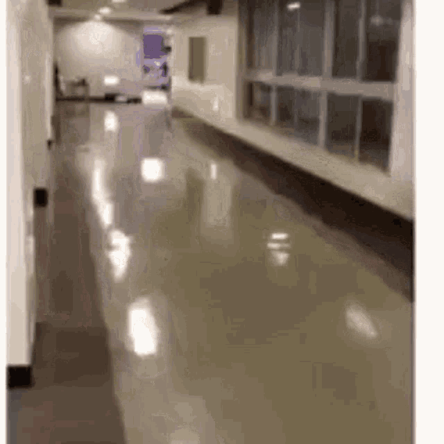 a long hallway with a lot of windows and a shiny floor in a building .