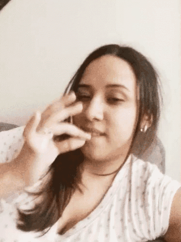 a woman is sitting on a couch smoking a cigarette and drinking a glass of wine .