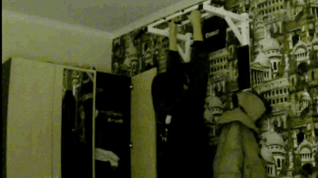 a person hangs upside down on a pull up bar in front of a city wallpaper