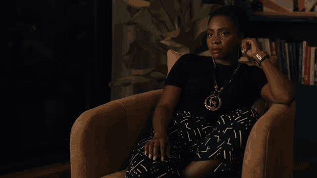 a woman is sitting in a chair wearing a black shirt and black pants