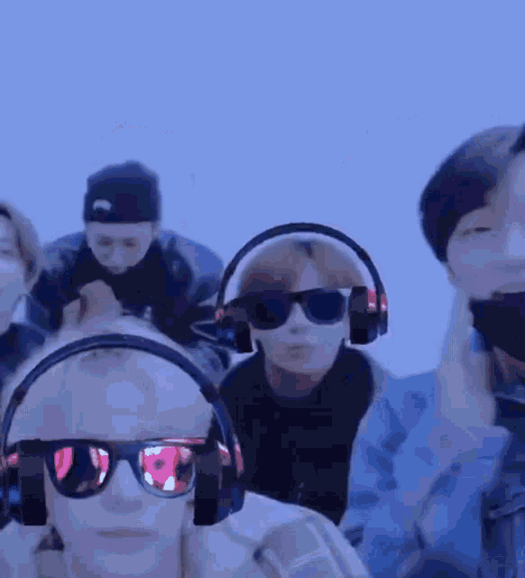 a group of young men wearing headphones and sunglasses are standing next to each other .
