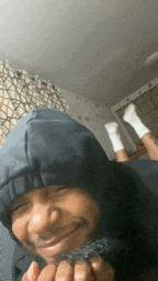 a man wearing a hoodie and white socks is laying on a bed .