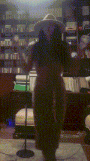 a naked woman wearing a hat is standing in front of a microphone