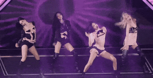 a group of women are dancing in front of a purple light