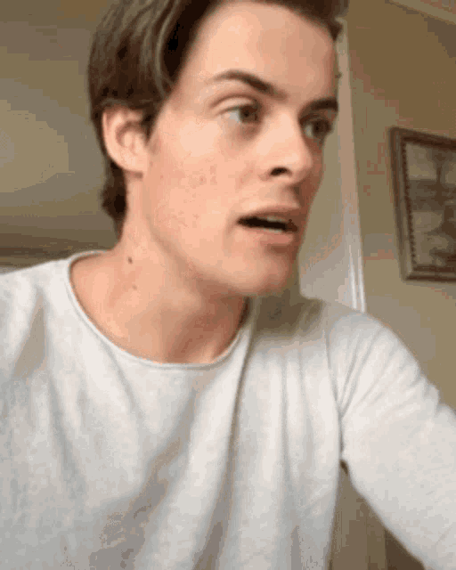 a man in a white shirt is making a surprised face