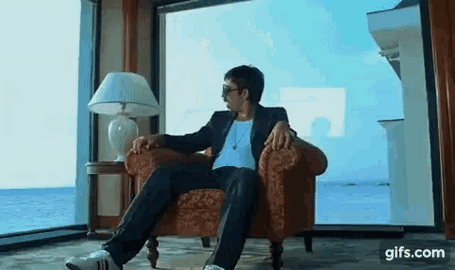 a man in a suit is sitting in a chair in front of a large window .