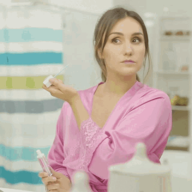 a woman in a pink robe is holding a toothbrush