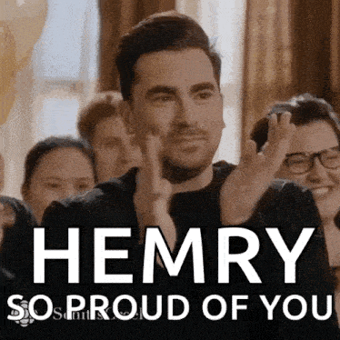 a man applauds in front of a group of people with the words henry so proud of you