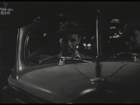 a black and white photo of a man driving a car