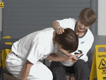 two men are playing with each other in front of a caution sign