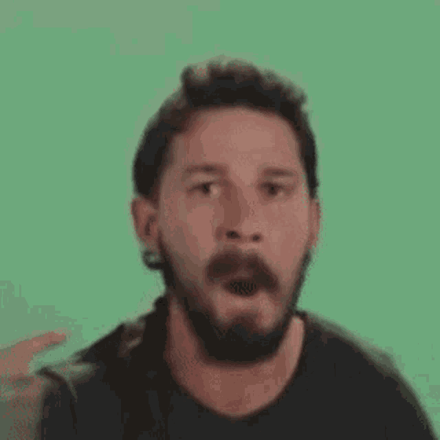 a man with a beard is making a funny face in front of a green background .
