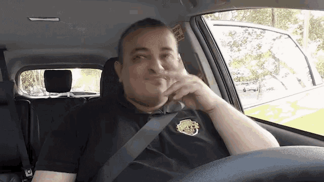 a man sitting in a car with a sticker on the back window that says " extra safety seat "