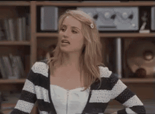 a woman is wearing a striped sweater and a white top .