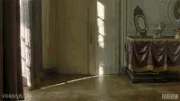 a room with a table and a mirror in it and a bbc logo on the wall .