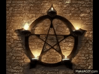 a pentagram on a brick wall with two candles in front of it