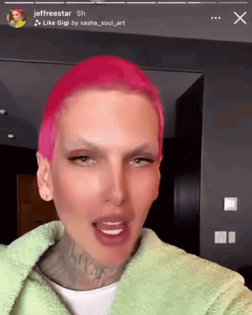 a man with pink hair is wearing a green robe and has a tattoo on his neck