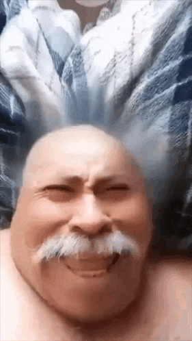 a bald man with a mustache is making a funny face with his head in the air .