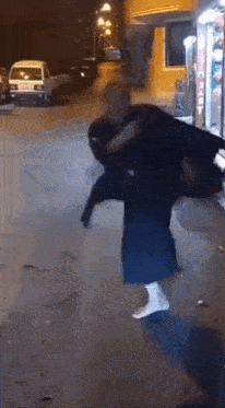 a man is carrying a woman on his shoulders on a street at night .