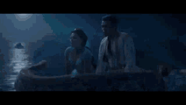 a man and a woman are sitting in a boat in the middle of the ocean .