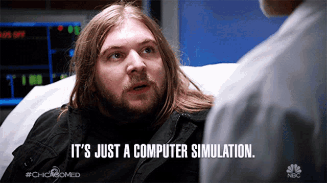 a man with long hair and a beard says it 's just a computer simulation while sitting in a hospital bed