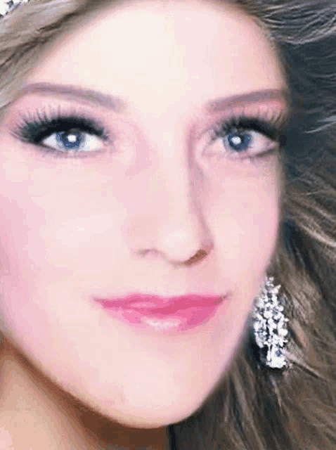 a close up of a woman 's face with blue eyes and pink lips