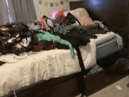 a bed with a lot of clothes on it and a sticker that says ' i love you ' on it