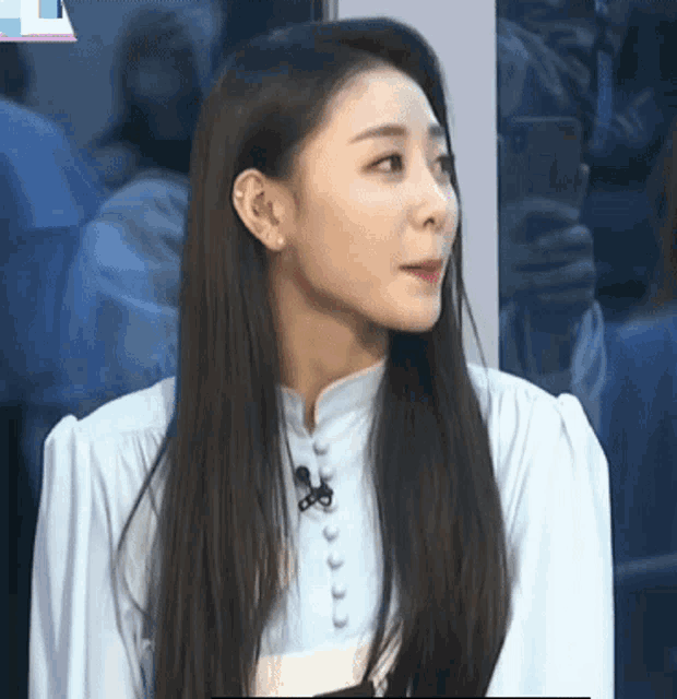 a woman with long black hair is wearing a blue shirt with buttons