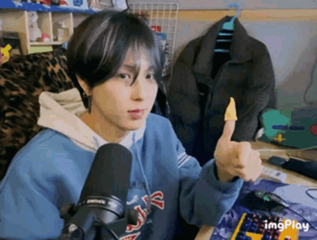 a person giving a thumbs up in front of a microphone with imgplay written on the bottom right