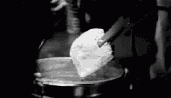 a black and white photo of a person pouring a liquid into a glass container .