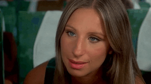 a woman with long hair and blue eyes is sitting on an airplane and smiling .