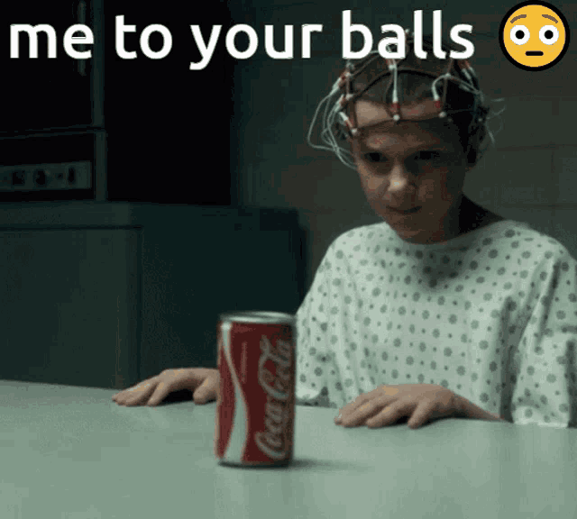 a girl in a hospital gown is sitting at a table with a can of coca cola