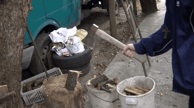 a person holding a large axe next to a bucket of firewood