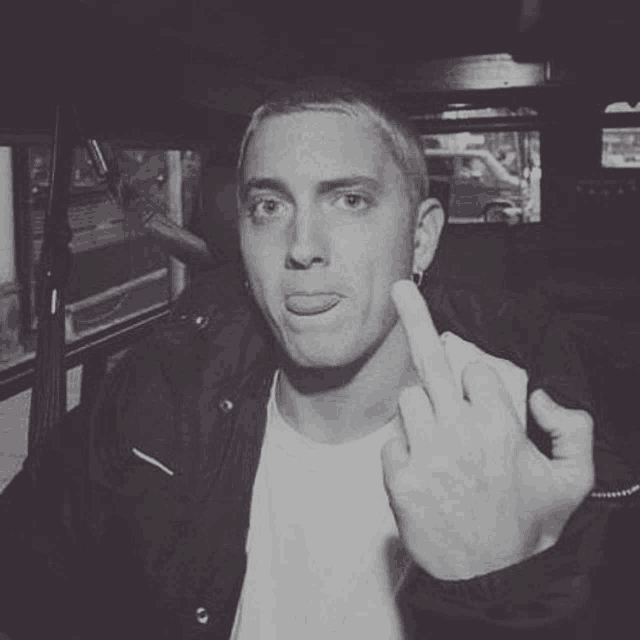 a man is sticking out his tongue and giving the middle finger .