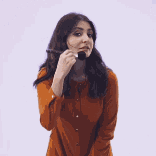 a woman in an orange dress is holding a brush in her hand