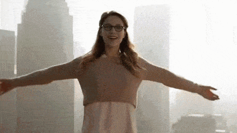 a woman is standing in front of a city with her arms outstretched .