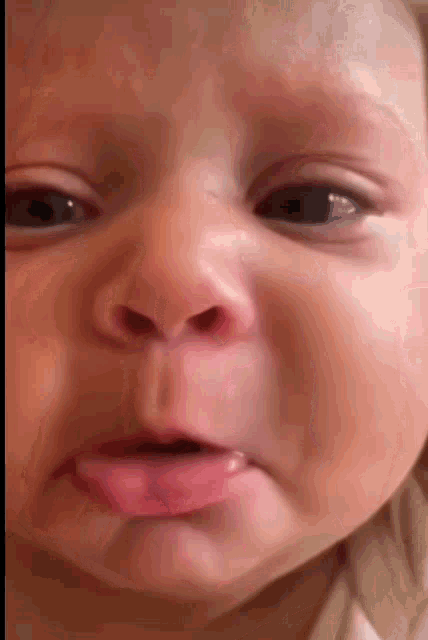 a close up of a baby 's face with his tongue sticking out .