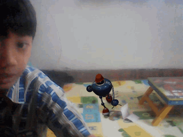 a boy in a plaid shirt is playing with a toy robot on a play mat
