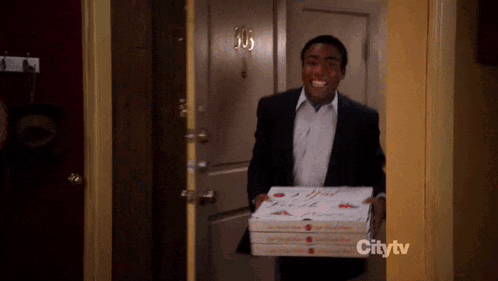 a man in a suit is carrying three boxes of pizza into a doorway .
