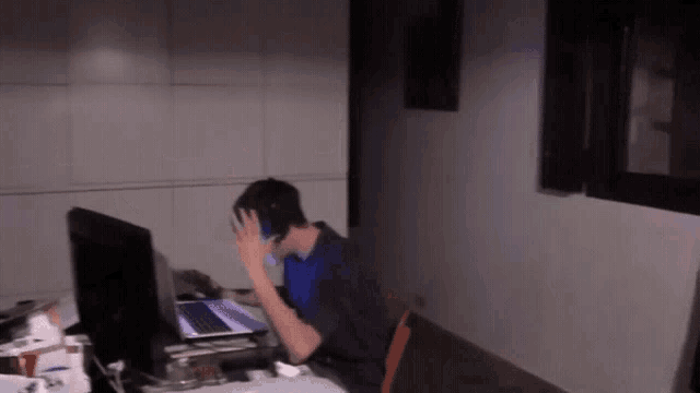 a man wearing headphones sits at a desk in front of a computer