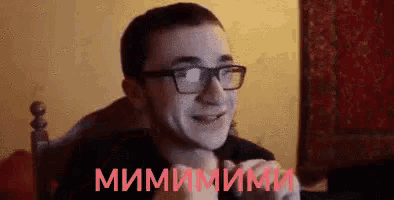 a man wearing glasses is sitting in a chair and smiling in a room .