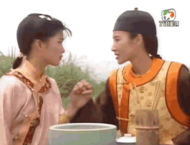 a man and a woman are holding hands in front of a bowl with tvb written on the bottom