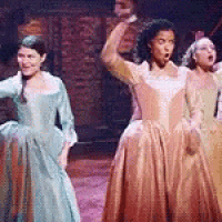 a group of women in dresses are standing on a stage and singing .