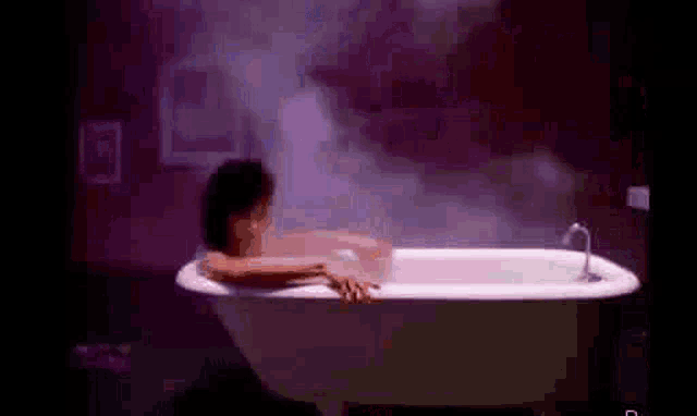 a woman is taking a bath in a bathtub with steam coming out of it .