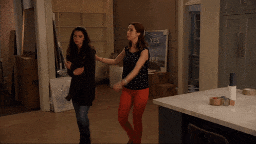two women are dancing in front of a sign that says yes you can