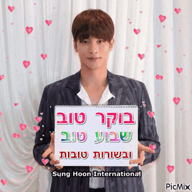 sung hoon international is holding a sign with hearts around him