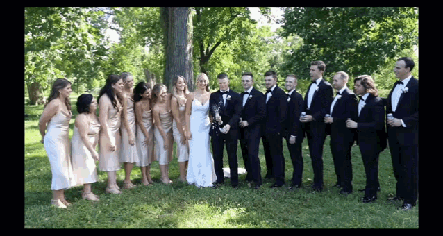 a bride and groom pose with their wedding party in front of a tree